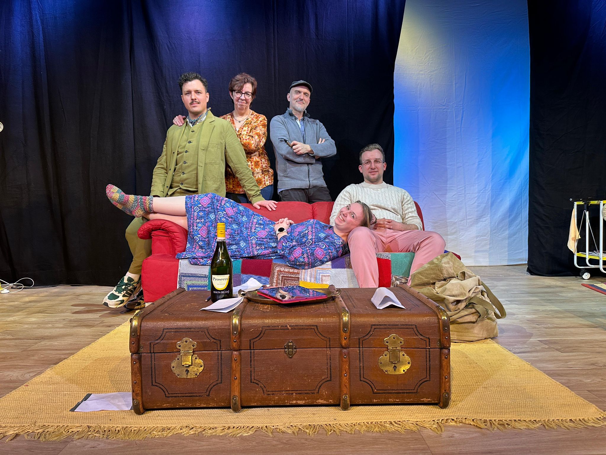 Ensemble der Theatergruppe Rohr auf der Bühne mit rotem Sofa und altem Reisekoffer Ensemble auf der Bühne