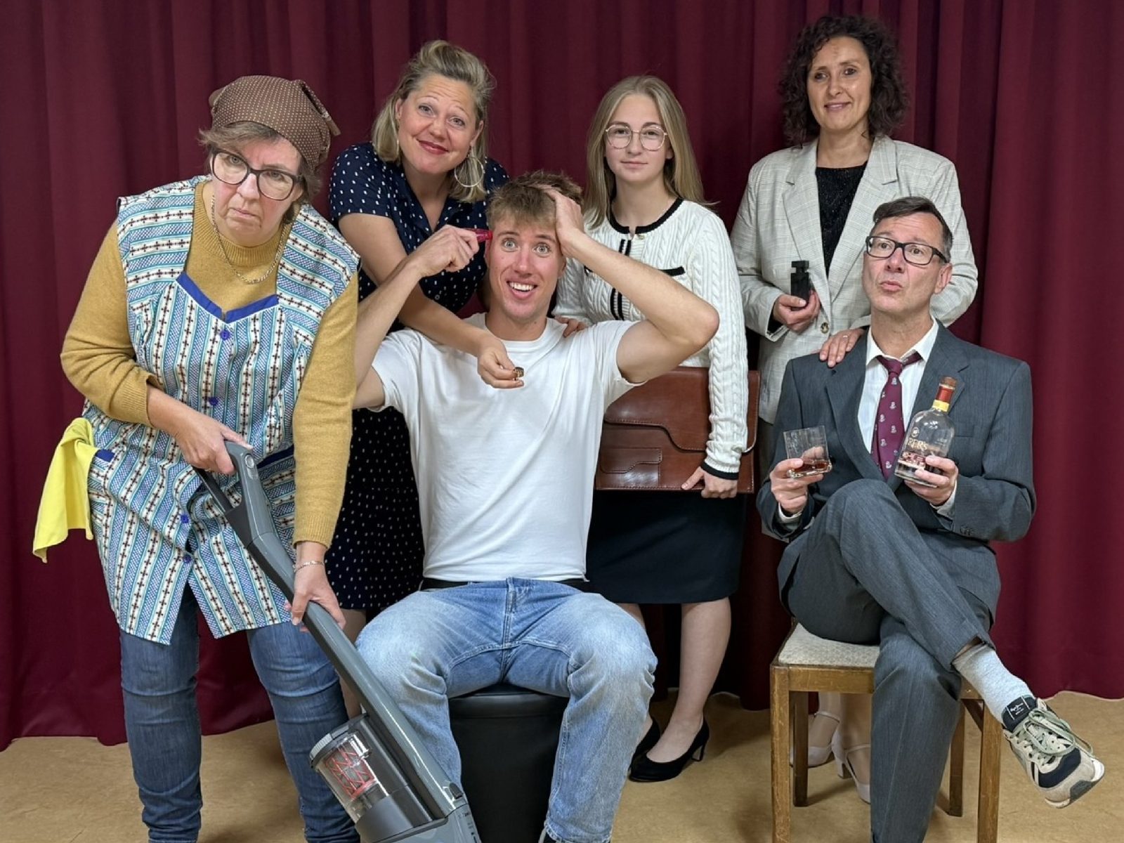 Job Suey: Das Ensemble vor dem roten Vorhang – Putzfrau mit Staubsauger, Jim Watt in der Mitte, sein Chef mit Whiskyglas