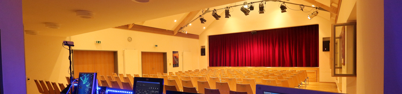 Saal und Bühne mit rotem Vorhang im Evangelischen Gemeindehaus Rohr