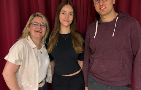 Vier aff amoll, Szenen „Du, horch“: drei Spielerinnen und Spieler vor dem roten Vorhang Vier aff amoll, Szenen „Du, horch“: drei Spielerinnen und Spieler vor dem roten Vorhang